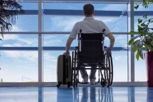 man in a wheelchair at the airport with his suitcase